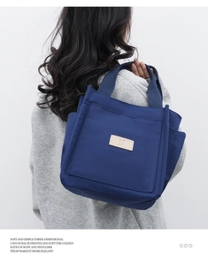 Detail view of a navy blue canvas tote bag featuring a leather logo patch and side pocket
