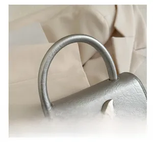 Detail of a silver leather handbag showing the textured bow and semi-circular handle
