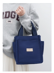 Detail of navy blue canvas tote bag showing side pocket and minimalist N logo patch