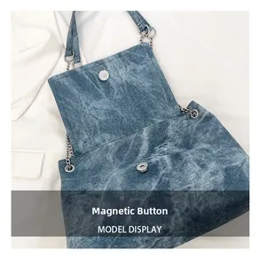 Detail of blue denim tote bag showing the magnetic snap button closure and silver chain