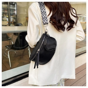 Detailed view of black lychee grain waist bag with geometric patterned strap on white suit