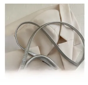 Detail of silver metallic textured handbag with cylindrical handle and adjustable strap