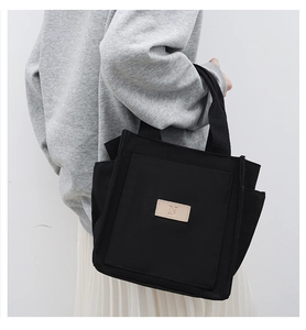 Detail of a black canvas tote bag showing side pockets and the minimalist N logo patch