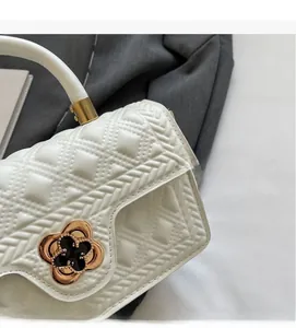 Detail der weißen gesteppten Ledertasche mit goldenem Blumenschloss und Tragegriff