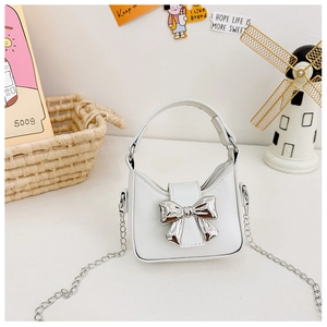 Detail of white mini PU leather handbag featuring a shiny silver metal bow and chain strap