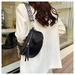 Black leather crescent bag with geometric strap and round coin purse on white suit