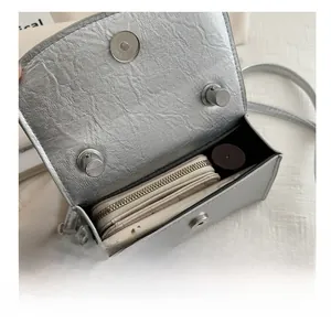 Detailed view of the silver crossbody bag interior showing phone, wallet and lipstick