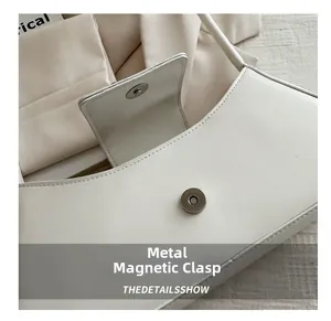 Détail de la fermeture à fermoir magnétique argenté sur un sac à bandoulière blanc