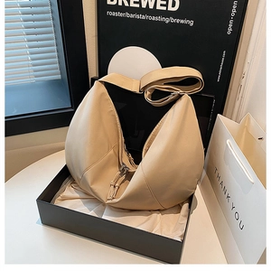 Detail view of beige crescent crossbody bag with zipper and adjustable wide strap