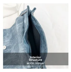 Detail view of denim tote bag showing internal structure, black lining, and silver chain strap