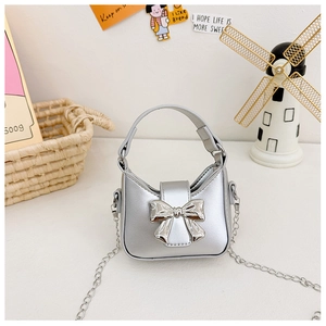 Close-up of metallic silver mini handbag featuring a mirror-finish bow and chain strap