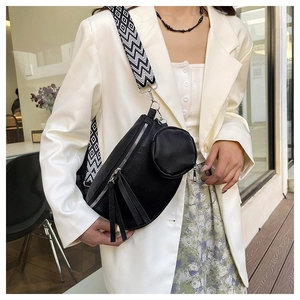 Detail of black pebbled leather crossbody bag with geometric woven strap and mini coin purse