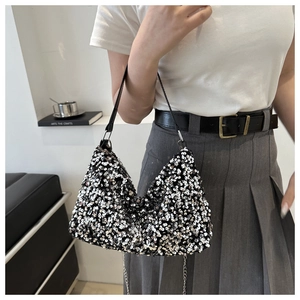 Gros plan des paillettes argentées et noires sur un sac à bandoulière tendance avec chaîne