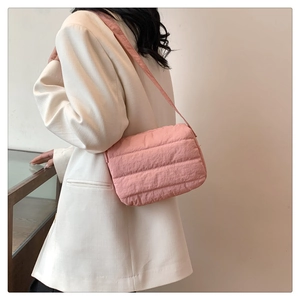 Detalle del bolso bandolera acolchado rosa en una modelo con una chaqueta blanca