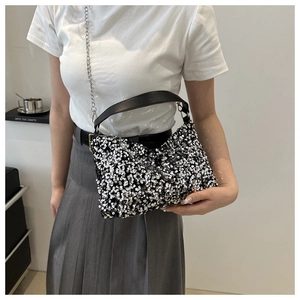 Détails d'un sac à main argenté à paillettes avec chaîne en métal et poignée en cuir
