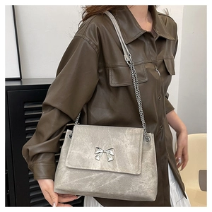 Detailed macro view of the silver-grey tote bag with butterfly buckle and chain strap