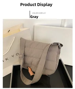 Detalle del bolso bandolera de nailon acolchado gris con costuras y textura de tela suave