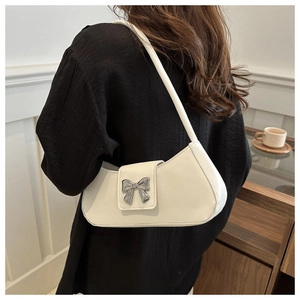 Détail d'un sac sous le bras en cuir blanc avec une boucle en métal en forme de nœud