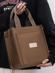Brown canvas tote bag with letter N detail and side pocket for casual commuting use