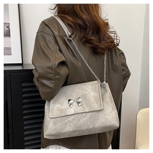 Detail view of grey textured tote bag with silver butterfly metal buckle and chain strap