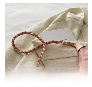 Detail of the soft pink pleated cloud bag featuring a wide braided leather shoulder strap