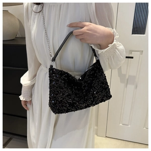 Détail du sac à bandoulière en paillettes noires avec chaîne argentée et texture brillante