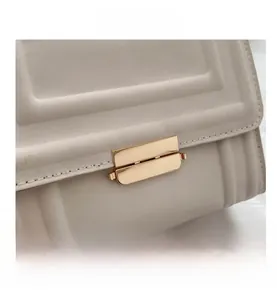 Close-up of cream white crossbody bag featuring vertical texture and golden metal lock