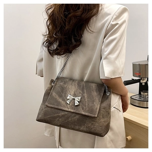 Detail of vintage brown tote bag with butterfly chain and metal accents on a desk
