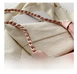 Detailed close-up of the woven strap and soft pink leather texture on a shoulder bag