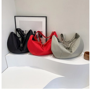 Three multi-colored minimalist crescent tote bags in black, red, and sage green displayed