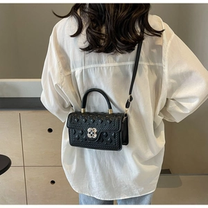 Detail der schwarzen Stepptasche mit goldener Blumenschnalle an einem Model