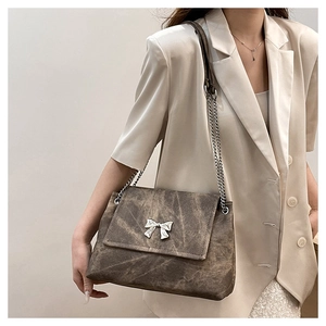 Detail of vintage brown tote bag with silver butterfly chain and distressed texture