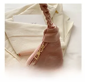Detail of pink pleated crescent bag showing metal zipper and woven handle texture
