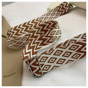 Detail of adjustable woven jacquard shoulder strap with geometric brown pattern and metal buckle