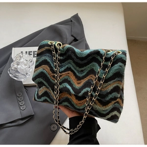 Detail of wave pattern knit tote bag with gold chain strap on grey suit background