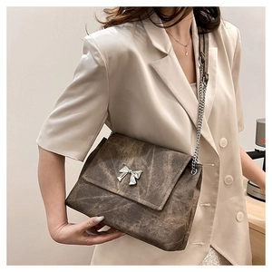 Detail of vintage brown tote bag featuring silver bow buckle and chain leather strap