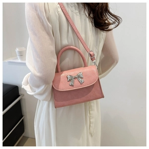 Detail of pink bow handbag featuring silver metallic knot and soft textured leather finish