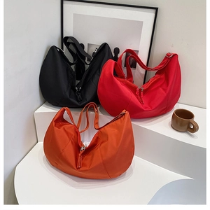 Three large nylon crescent bags in black, red, and orange shown on a tiered display