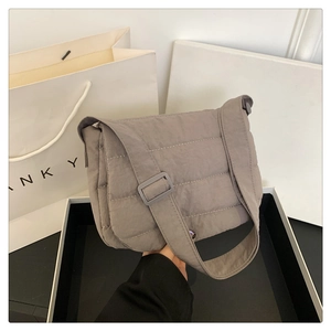 Detalle del bolso de hombro acolchado gris con textura suave y correa ajustable