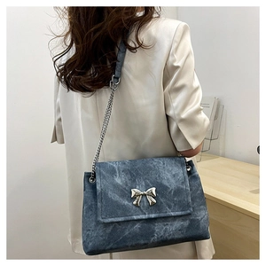 Detail of blue denim shoulder bag with silver butterfly buckle and metal chain strap