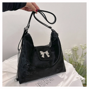 Close-up of black velvet tote bag featuring a silver metal bow detail and zipper closure