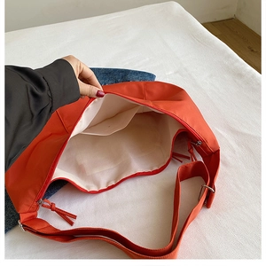 Interior view of orange nylon dumpling bag showing large capacity and cream lining