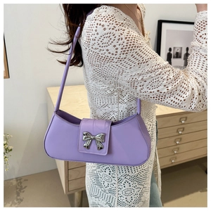 Détail du sac sous le bras violet avec noeud métallique argenté porté par un mannequin