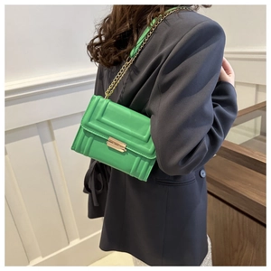 Fashionable green quilted crossbody bag with gold chain strap shown on a model