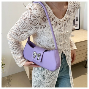 Détail d'un sac violet avec boucle nœud en métal argenté sur un rabat en cuir lisse élégant