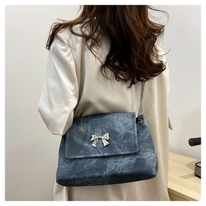 Detail of blue marble texture shoulder bag featuring silver butterfly chain decoration