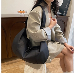 Detailed view of black nylon hobo bag featuring wide adjustable strap and silver zipper