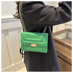 Detail of bright green crossbody bag with geometric embossing and gold chain strap