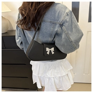 Détail d'un sac sous le bras en cuir PU noir avec un nœud en métal argenté sur l'épaule