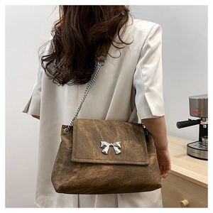 Detail of vintage brown leather tote bag with silver butterfly charm on a model